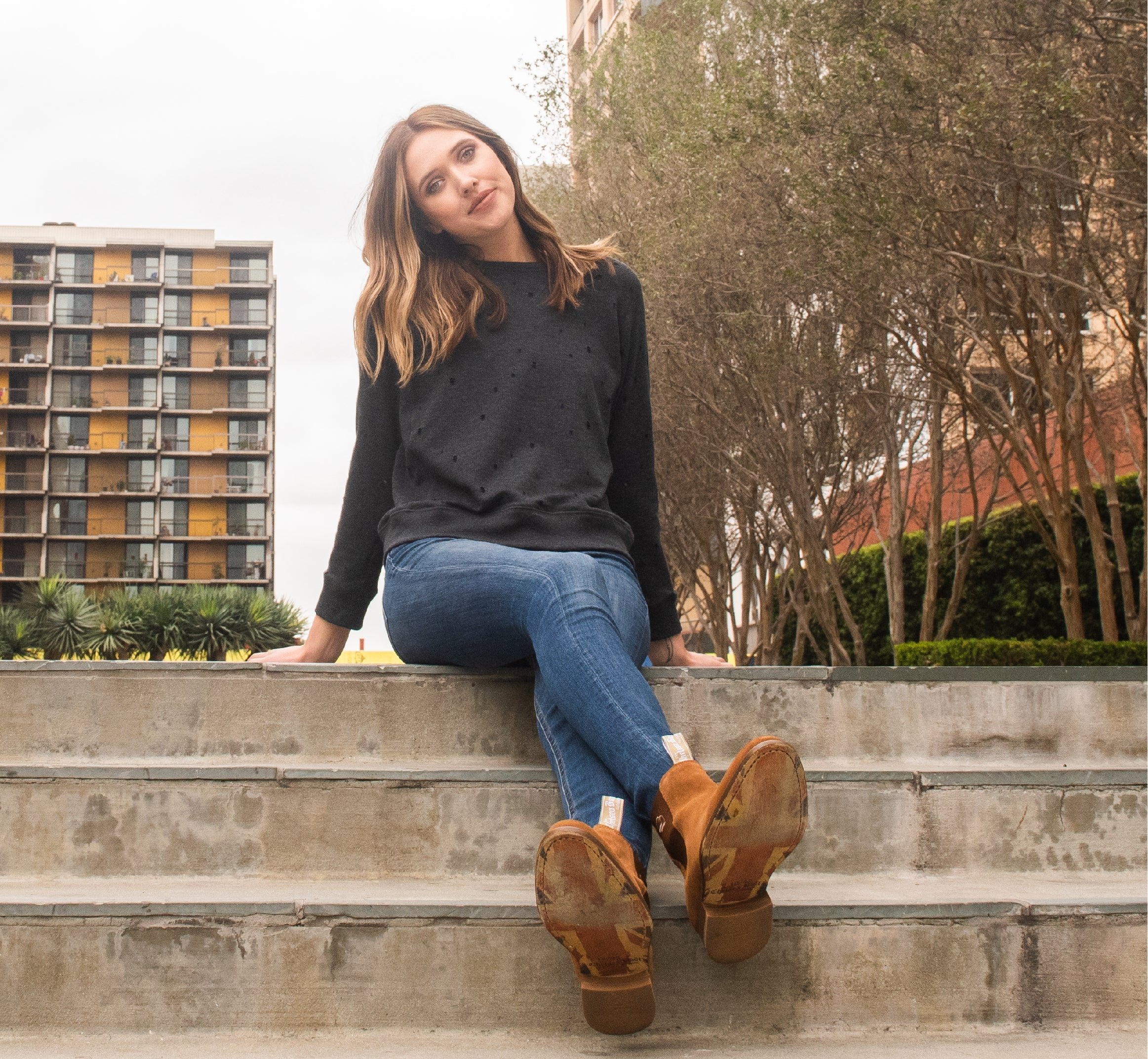 Model sitting on some steps wearing a pair of Tan Suede Chelsea Boots with the Union Jack sole showing in the photo.